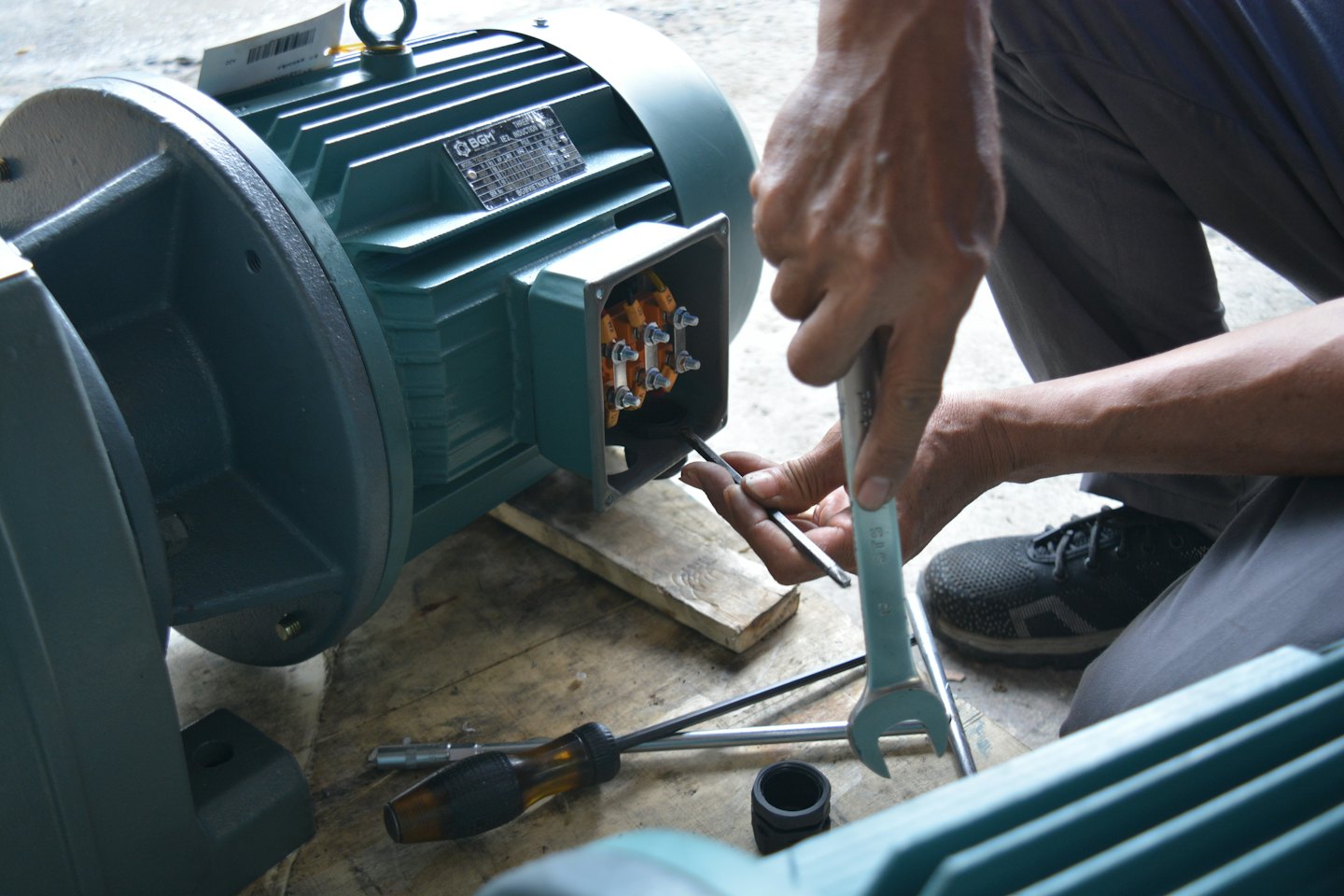 Technician's hands connecting wires in an industrial electric motor.