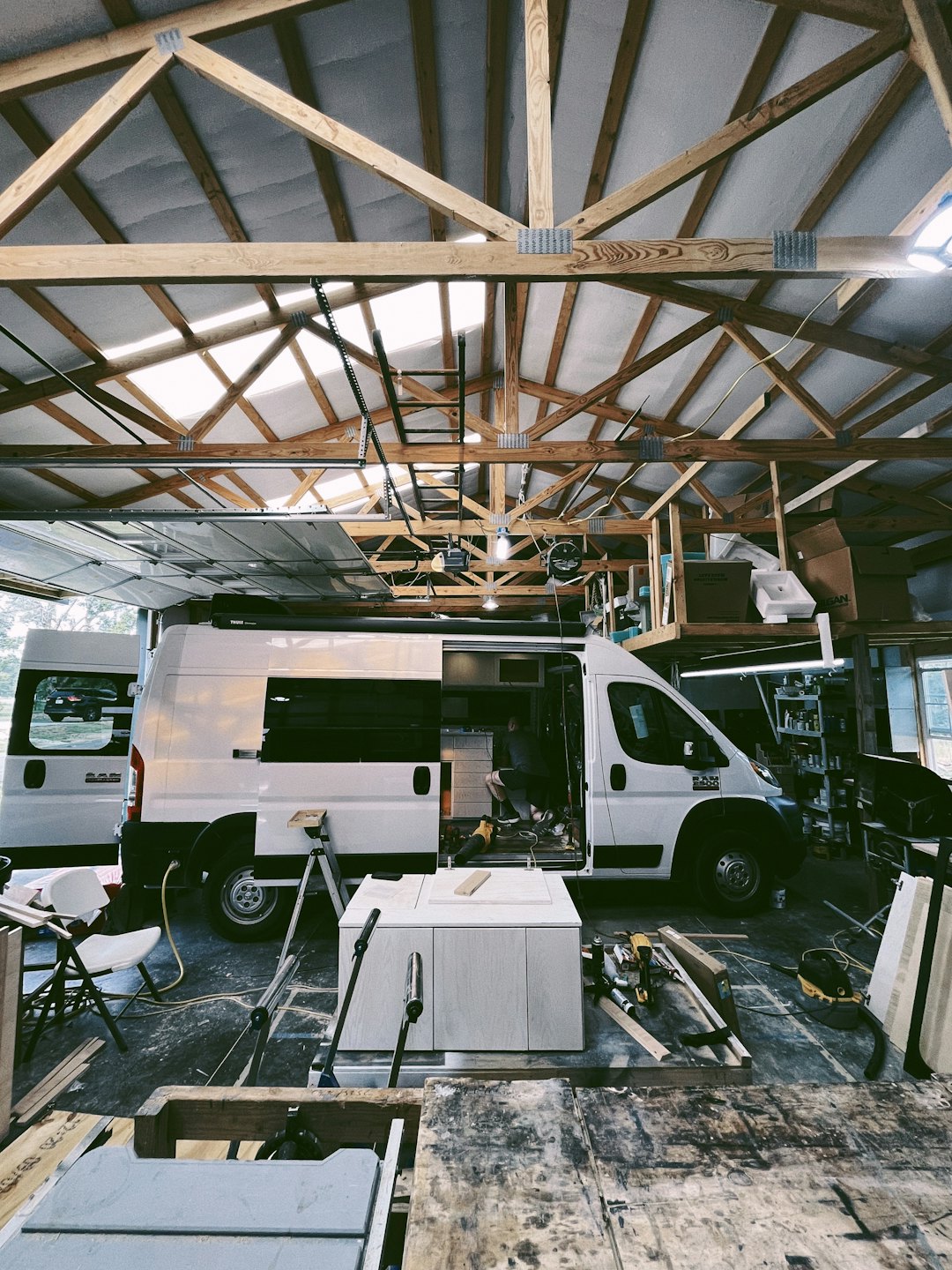 Person building custom cabinets inside a white RAM ProMaster van.