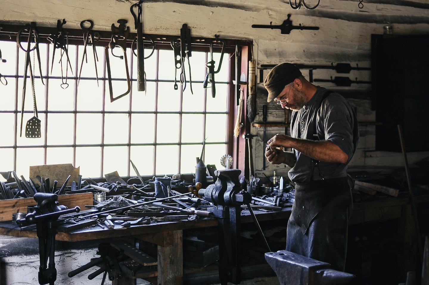 Craftsman meticulously working on a small object at his workbench.