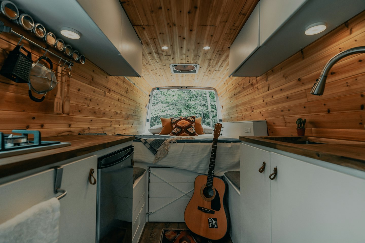 Cozy camper van interior with wood walls and a bed.
